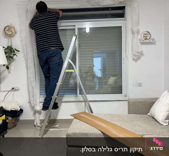 אדם על סולם מתקן תריס בחדר מגורים